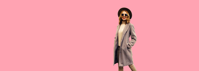 Beautiful stylish smiling young woman model wearing brown round hat and coat on pink background, banner blank copy space for advertising text