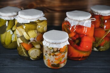 Jars of pickled vegetables on rustic wooden background