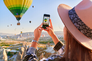 Girl tourist vacations in beautiful destination in Goreme, Turkey. Taking photo of flying air...