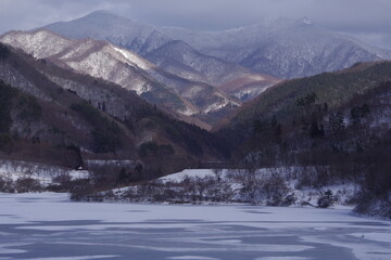 Fototapeta na wymiar Winter lake and mountain snow scene. Winter afternoon landscape photo.