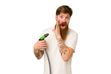 Adult man holding a watering hose isolated is saying a secret hot braking news and looking aside