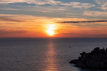 Fototapeta premium Panoramic sunset view at Adriatic Mediterranean Sea near Sveti Stefan, Budva Riviera, Montenegro, Europe. Reflection of sun beams on water surface during twilight. Summer vacation in seaside resort