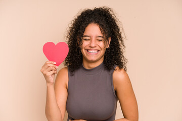 Young african american woman holding a heart for valentines day isolated laughing and having fun.