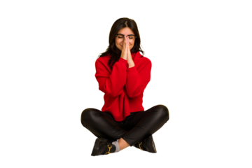 Young indian woman sitting on the floor cut out isolated holding hands in pray near mouth, feels confident.