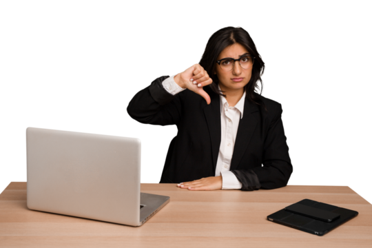 Young indian woman in a table with a laptop and tablet isolated showing a dislike gesture, thumbs down. Disagreement concept.