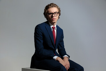 sexy young businessman with glasses sitting and posing