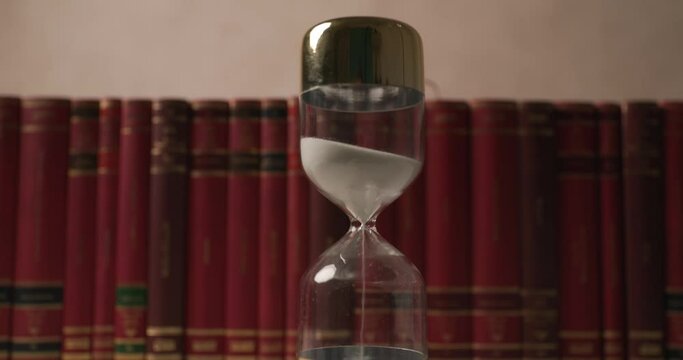 concept video of hourglass in front of university row books illustrated by time pressure and running out of time before an important exam
