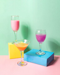 Colorful cocktails on pastel light pink and green background. Creative drink concept. Minimalistic beverage composition.