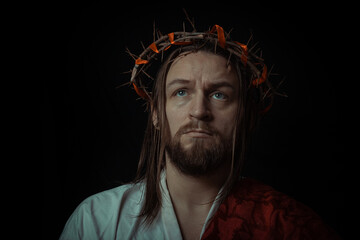 Fototapeta premium Jesus Christ wearing a crown of thorns and white chiton toga mantle cape himation suffering for mankind's sins in artistic mystical portrait