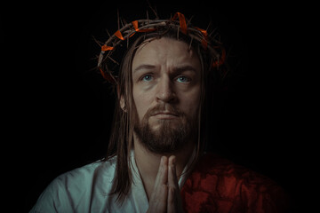 Fototapeta premium Jesus Christ wearing a crown of thorns and white chiton toga mantle cape himation suffering for mankind's sins in artistic mystical portrait
