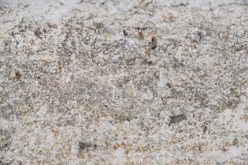 Old, gray concrete wall with peeling white paint.
