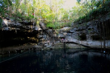Fototapeta na wymiar Cenote Xcanche is a stunning open cenote with swimming, zip-lining and swing jumps , there is also a waterfall cascading into the cenote. Located near Valladolid the Yucatan Peninsula , 14 11 2022.