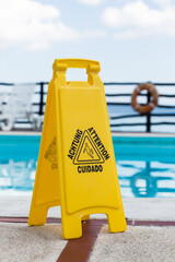 Wet floor warning sign near a swimming pool at poolside