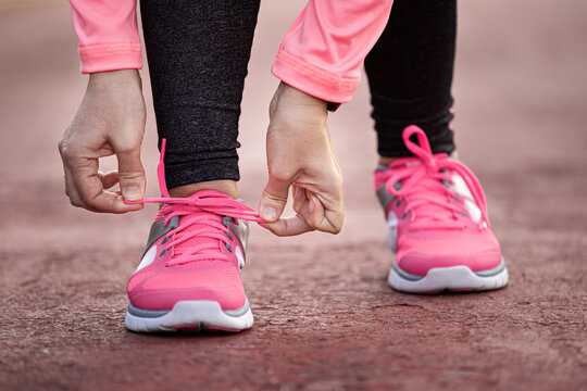 Runner woman tying up laces of shoes, getting ready to run for cardio and weight loss © photopixel