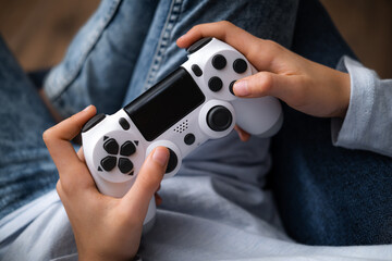 kids hands with joystick, child playing video game console while sitting at home, real people, leisure concept.