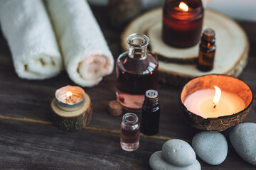 Concept of natural essential organic oils, Bali spa, beauty treatment, relax time. Atmosphere of relaxation, pleasure. Candles, towels, dark wooden background. Alternative oriental medicine