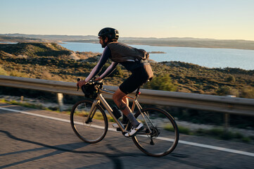 Man rides a gravel bike on the road at sunset.Empty city road.
Sports motivation.Murcia region in Spain