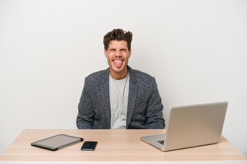 Young entrepreneur man working with a laptop isolated funny and friendly sticking out tongue.