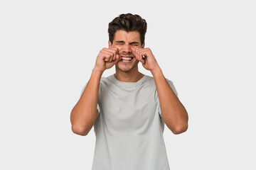 Young handsome caucasian man isolated on white background whining and crying disconsolately.