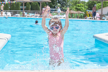 child girl 3 years old swims in the pool in the summer outdoors