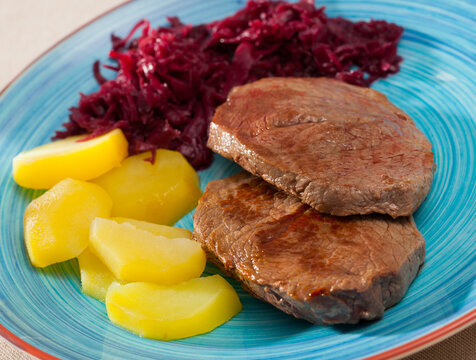 Veal Medallion de cadera with potato and sauerkraut..Healthy roasted beef steak served with baked potatoes and pickled cabbage..Grilled veal steak with boiled potato and marinated cabbage