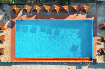 Empty rectangular blue swimming pool with sunbeds and umbrellas on a sunny summer day. Travel,...