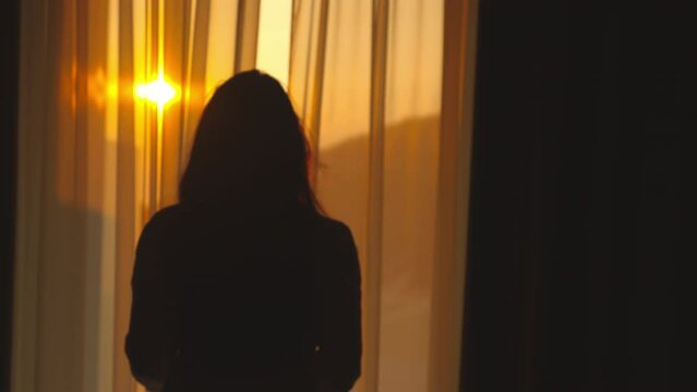 Woman walking in slow-motion to the tarrace for enjoying sunset at beach side. Woman looking at view of sea from balcony