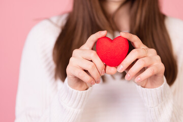 girl holding a heart in her hands close-up on a pink background, the concept of valentine's day