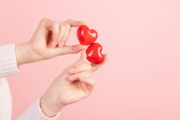 closeup hands holding heart on pink background, valentine's day concept