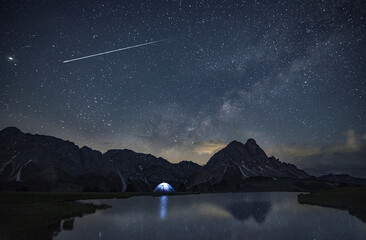 Shooting stars cross the night sky above the mountains