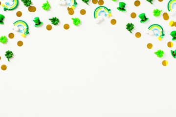 Happy St Patrick's Day concept. Frame made of confetti, rainbows, hats, decorations on white table.