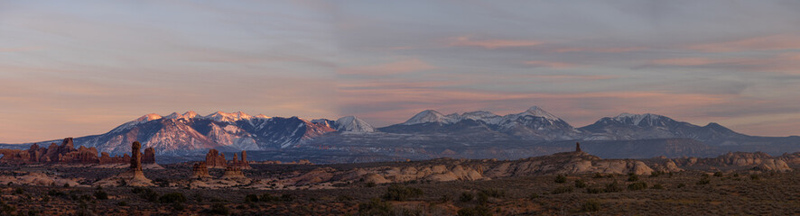 Panorama of rock formations with distant snow-covered mountains in the distance in Arches National Park.