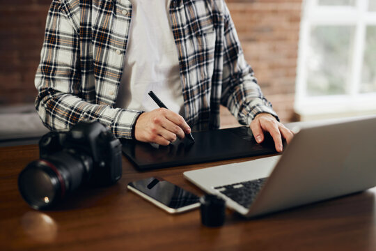 A professional photographer or graphic designer is sitting at his office desk. Man in office with digital graphics tablet and pen for drawing.