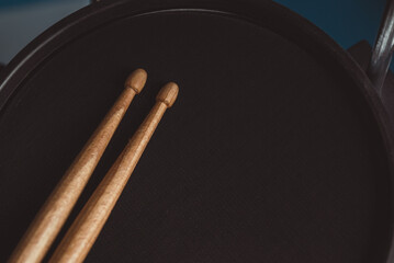 Close up picture of brown drum sticks on the black drum. Detail of snare drum drum sticks. Percussion musical instruments. Soft focus. Music concept and beats waiting to happen.