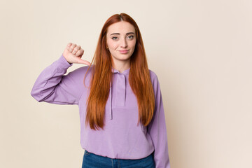 Young red hair woman isolated showing a dislike gesture, thumbs down. Disagreement concept.