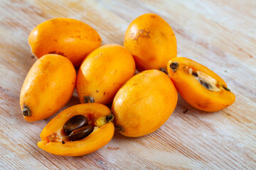 Naklejka na ściany i meble Fresh juicy whole and halved Japanese medlar fruits on wooden table. Spring vitamin product