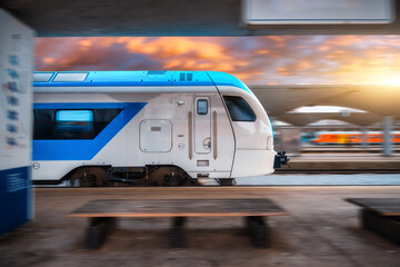 Blue high speed train in motion on the railway station at sunset. Fast modern intercity train and...