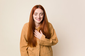 Obraz premium Young red hair woman isolated laughs out loudly keeping hand on chest.