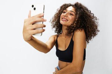 Woman blogger with phone in hand on white background selfies, video call, freelancer influencer job in social media and media, technology for work, smile curly hair copy spot