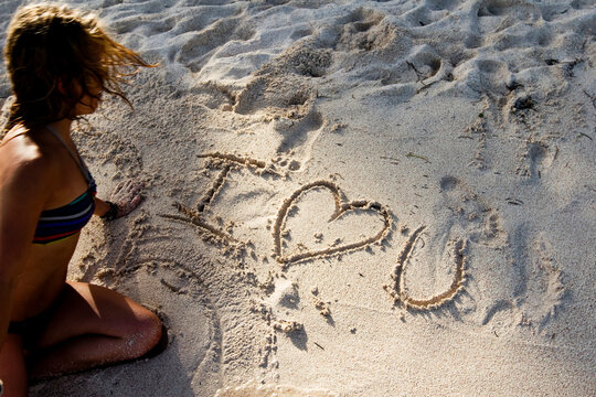 Woman writes I love you on the beach in Mexico.