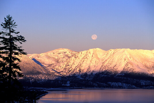 The moon over the lake at sunrise in Lake Tahoe, California.