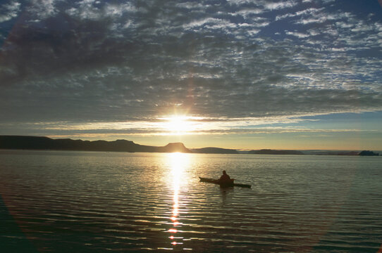 An Inuit hunter stalks Narwhal from his sea kayak.