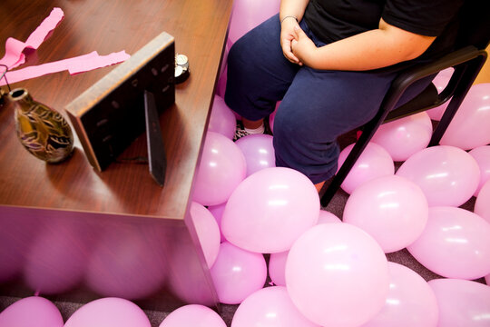 Reedley, California, United States.  An obese teenager sits in an office filled with balloons.