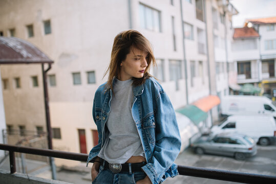 Hipster girl leaning against a railing with building on the background