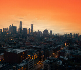 Crowded buildings of the New York City skyline with warm yellow orange sky above the downtown skyscrapers of Manhattan