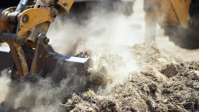 Industrial excavator loading soil material on a highway construction site into a dumper truck, slow motion