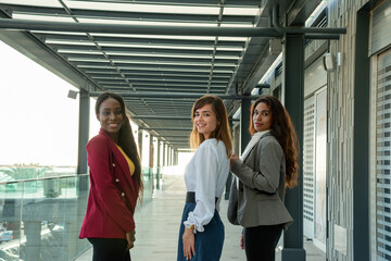 Three young businesswomen turn towards the camera during a meeting in the trade center.
