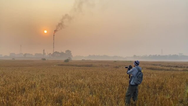 Photojournalist taking photos of industry area in Bangladesh, standing on field