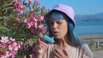 A teenager with an asthma attack. A teenage girl with blue hair is suffocating while near the flowers on the seashore.