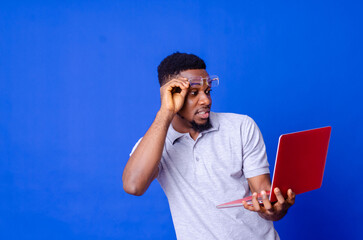 Young surprised african american man standing and using laptop computer